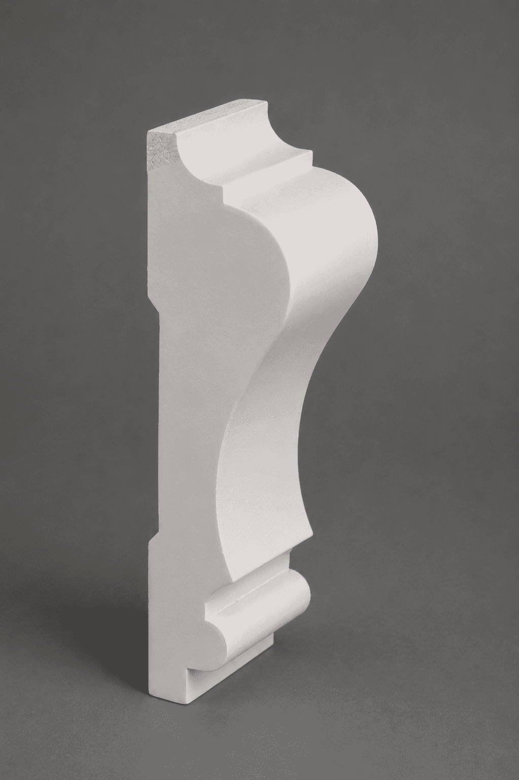 Primed white crown moulding standing on end, showing its cove, step and bead profile