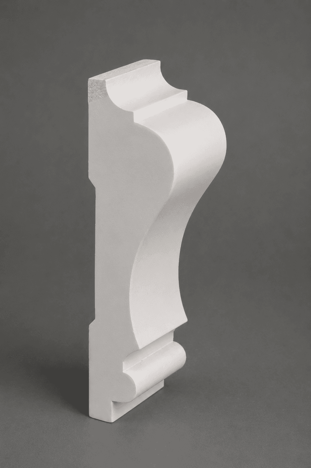 Primed white crown moulding standing on end, showing its cove, step and bead profile