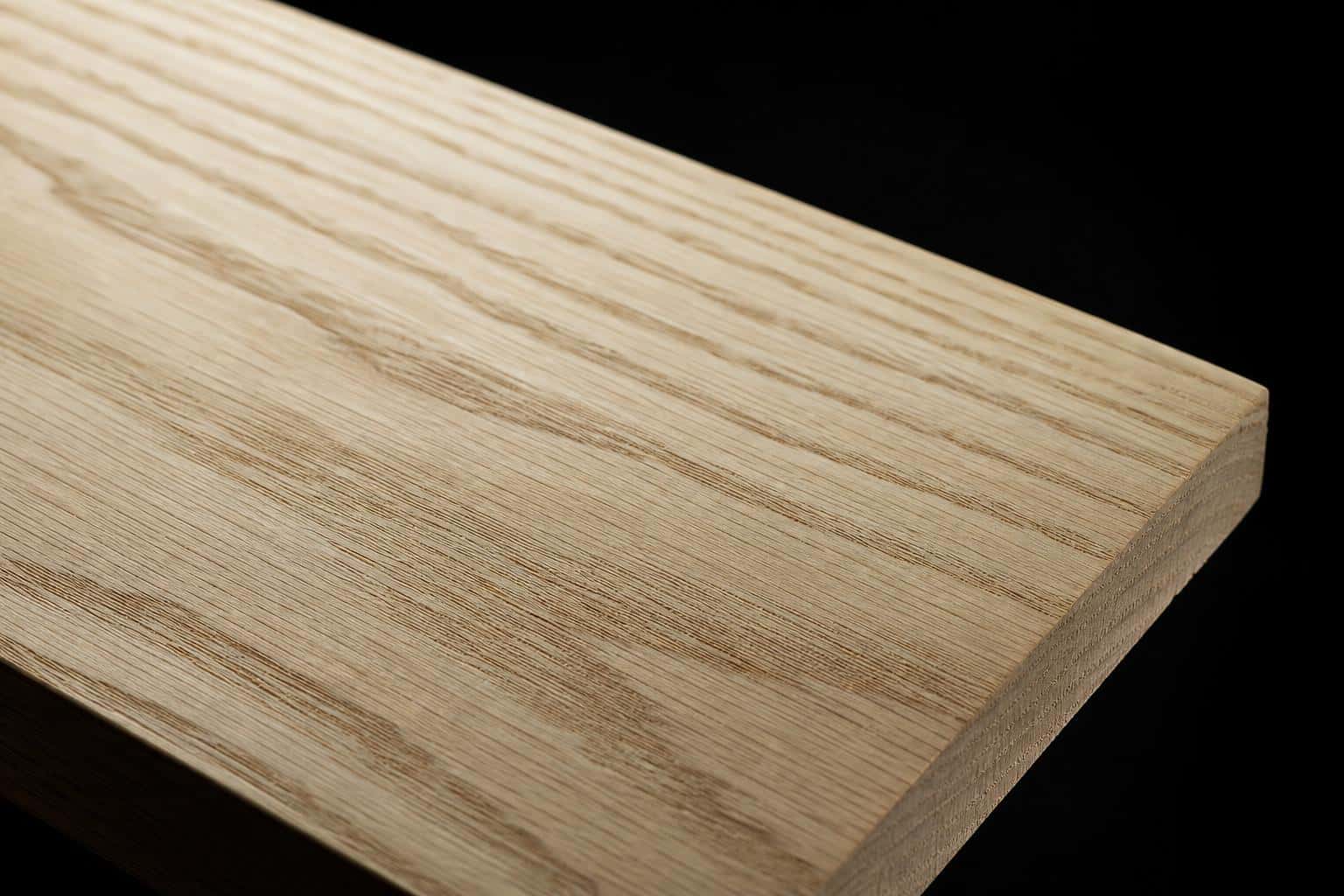 White ash board with a pale face and bold, open cathedral grain, close-up of the face and edge