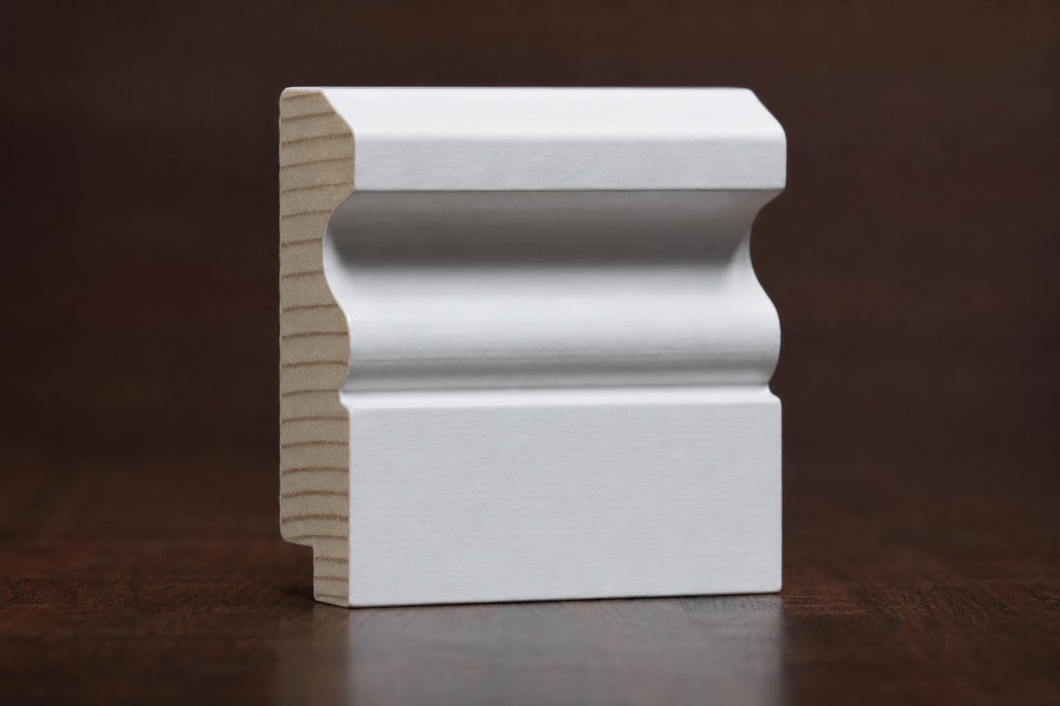Primed white door casing with a cove and bead profile, cut end showing the bare wood