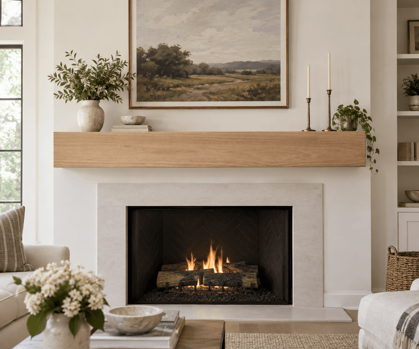 Smooth light wood box mantel above a lit fireplace, with candlesticks and a landscape painting on top