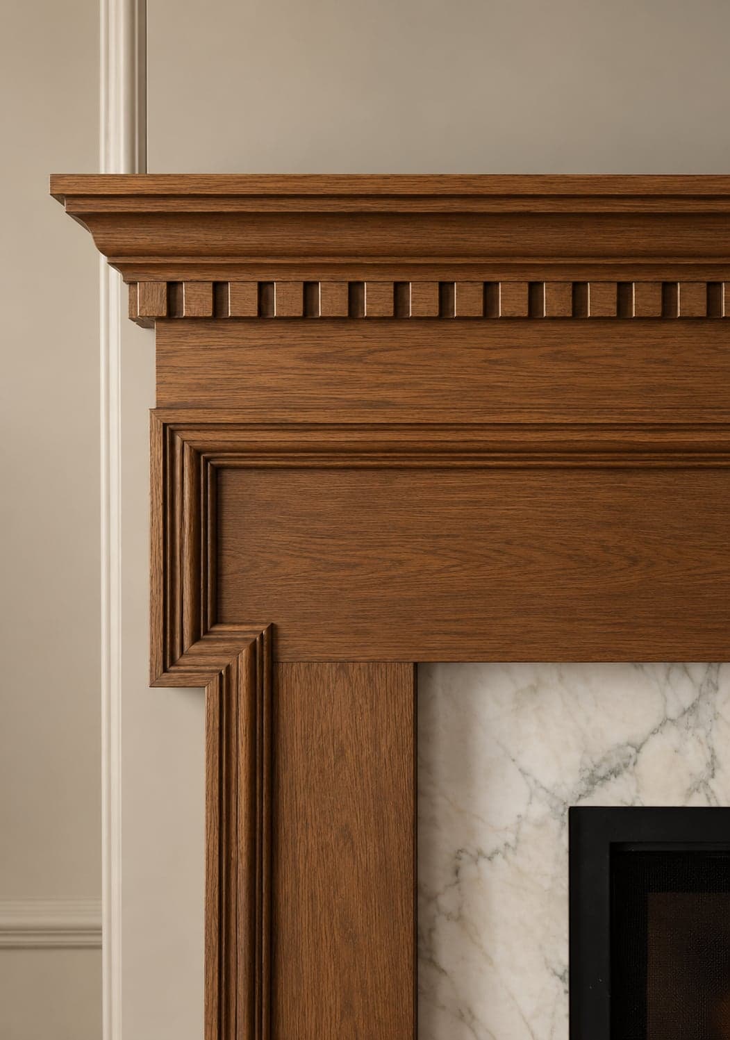 Close-up of a stained wood fireplace mantel with a dentil moulding band and a marble surround