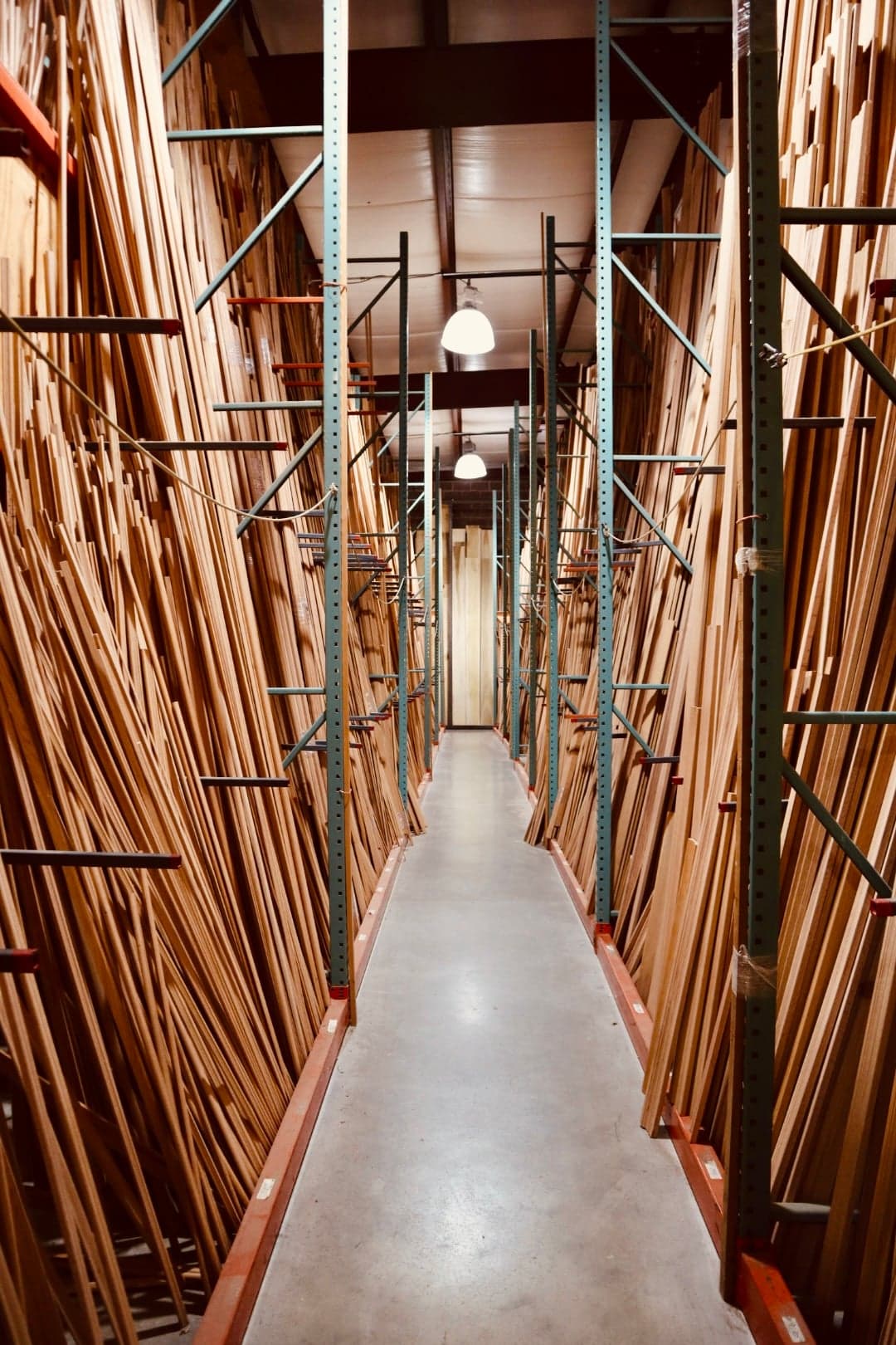 Long aisle between tall racks of hardwood moulding stock stored on end